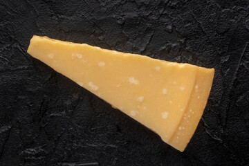 Parmesan cheese wedge, overhead flat lay shot, a black slate background