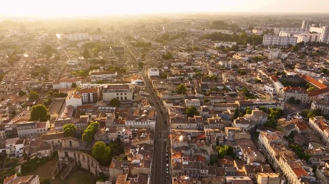 Aerial view of the cityscape with its buildings, streets, and railway tracks bathed in the warm glow of the setting sun, Bordeaux, Nouvelle-Aquitaine, France.