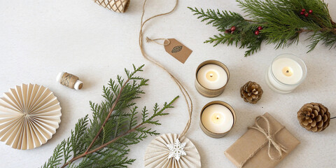 Christmas gift tags with fir branches, pine cones, wooden ornaments and lit candles arranged on gray background creating cozy winter holiday atmosphere for seasonal designs.