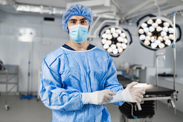 A surgeon wearing a mask and surgical gown prepares for an operation in a modern operating room.