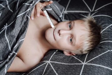 A handsome blond boy is lying in bed