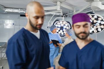 Medical team in an operating room setting, with surgeons and surgical lights visible.