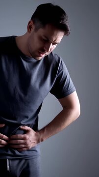 Man having pains in stomach. Young man suffering from a belly ache. Cropped shot of a sick man with an ulcer, IBS, colitis, or dyspepsia holding hands on his abdomen. Health problems concept