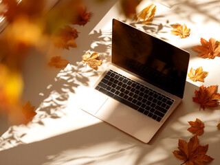  Laptop surrounded by colorful autumn leaves on light background, creating cozy fall atmosphere with soft sunlight.