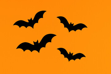 Naklejka premium Flying Black Bats Silhouettes on Bright Orange Background - Halloween and Spooky Night Theme