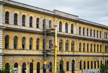Naklejka premium Historic yellow building under renovation with scaffolding and waste chute in Rome