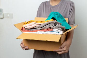 Donation Concept, woman holding clothes with donate box in white background room.