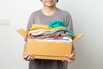Donation Concept, woman holding clothes with donate box in white background room.