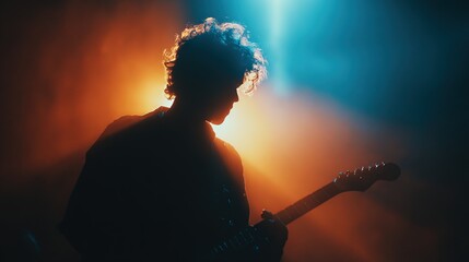 A silhouetted musician plays guitar against a colorful, dramatic background of blue and orange lights, creating a vibrant concert atmosphere.
