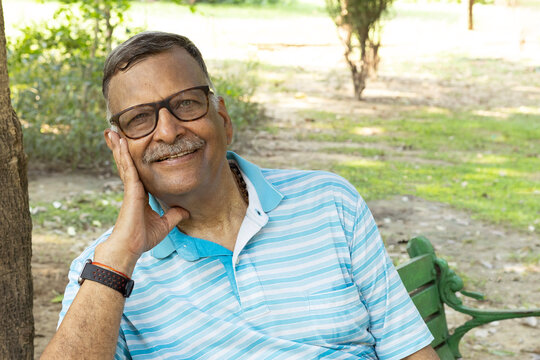 Indian happy Senior old man sitting and smiling at park