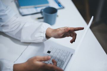 Middle aged female doctor working on laptop in doctor's room