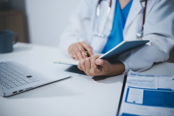 Fototapeta premium Middle aged female doctor working on laptop in doctor's room