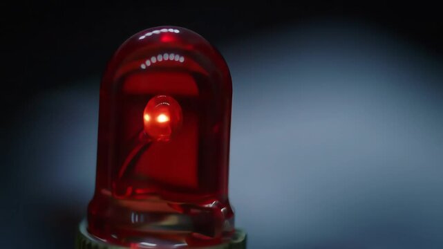 A closeup shot of a bright red emergency siren light flashing and rotating indicating an alarm or critical situation with a dark and blurred background.