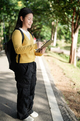 Obraz premium beautiful Asian girl student holding tablet and smiling at camera and learning and education concept on park in summer for relax time