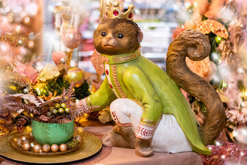 A fairytale Christmas background with a crowned monkey figurine against a sparkling festive backdrop, selective focus. A magical Christmas show in beautiful pastel colors