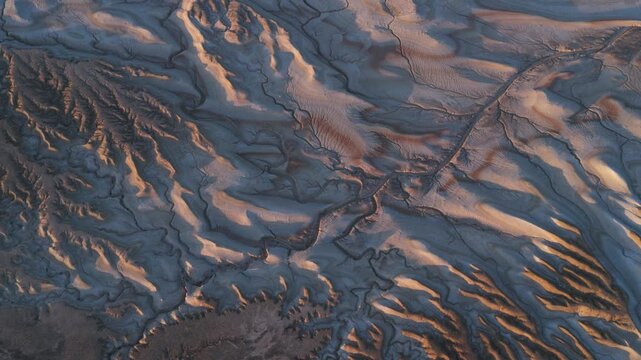 Aerial view of an arid landscape with cracked earth textures, creating a network of natural patterns in contrasting light and shadow, Tiramisu, Mangystau Region, Kazakhstan.