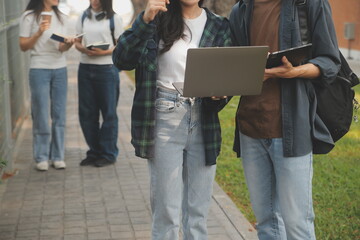 Happy students walking together on university campus, chatting and laughing outdoors after classes