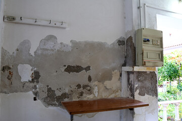 Severely Damaged Wall with Plaster Loss and Moisture Stains Caused by Rising Capillary Damp, Highly Dangerous Due to Nearby Electrical Panel