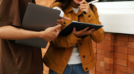 Happy students walking together on university campus, chatting and laughing outdoors after classes