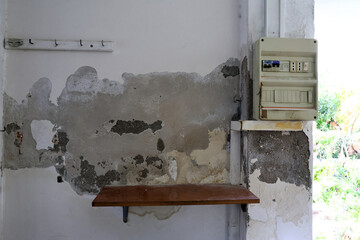 Severely Damaged Wall with Plaster Loss and Moisture Stains Caused by Rising Capillary Damp, Highly Dangerous Due to Nearby Electrical Panel