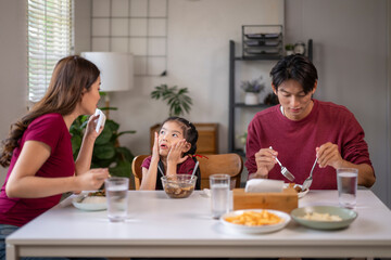Asian family eating meal facing picky bored child
