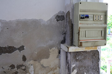 Severely Damaged Wall with Plaster Loss and Moisture Stains Caused by Rising Capillary Damp, Highly Dangerous Due to Nearby Electrical Panel