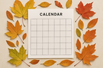 Autumn leaves around empty calendar sheet with clean grid on beige background, ready for planning or marking events.