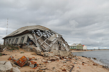 An abandoned and collapsing old house stands on a sandy beach with threatening stormy skies looming...