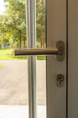 Exit glass door as seen from inside. Door handle and walkway, trees in the background. Vertical shot.
