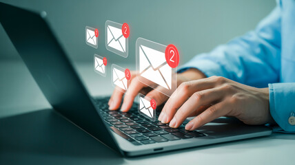 Person typing on laptop with floating email notification icons with unread messages inbox communication