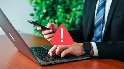 Person using laptop and smartphone with red warning alert symbol overlay danger caution