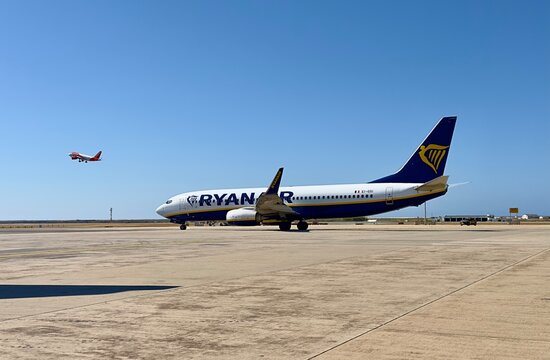 Faro, Portugal - May 24, 2025; A Ryanair aircraft on the ground preparing for departure as an EasyJet plane climbs into the sky in the background, Faro Airport, Portugal. 