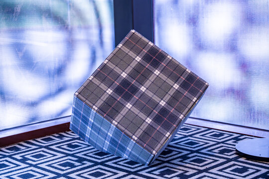Cube recouvert de tissu tartan, mettant en valeur le motif &eacute;cossais classique et la texture textile riche.
