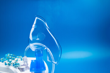 A close-up side view of a blue mask with steam coming out and a device on a blue background with...