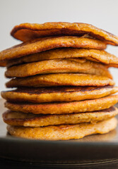 A close-up stock photo of a stack of fluffy pumpkin spice pancakes topped with syrup