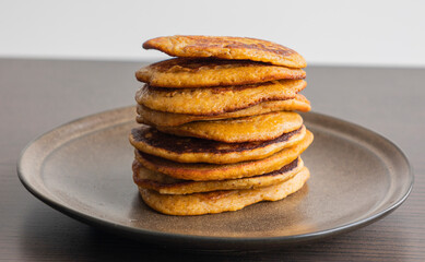 A close-up stock photo of a stack of fluffy pumpkin spice pancakes topped with syrup
