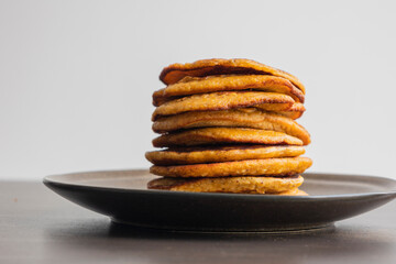 A close-up stock photo of a stack of fluffy pumpkin spice pancakes topped with syrup