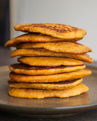A close-up stock photo of a stack of fluffy pumpkin spice pancakes topped with syrup