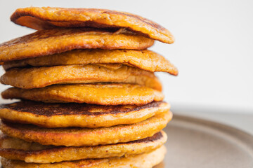 A close-up stock photo of a stack of fluffy pumpkin spice pancakes topped with syrup