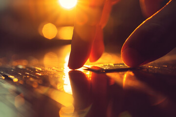 Touch of Technology: A hand delicately interacts with a microchip, the warm sun casting a radiant glow upon the scene, representing the intersection of human ingenuity and technological advancement.