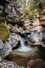 Obraz premium A serene mountain stream cascading through rocky terrain, capturing nature's beauty and tranquility.