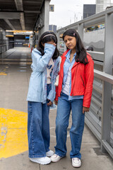 Two teenagers in blue and red jackets pose for a picture