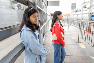 Two teenagers standing on a sidewalk, one wearing a blue jacket