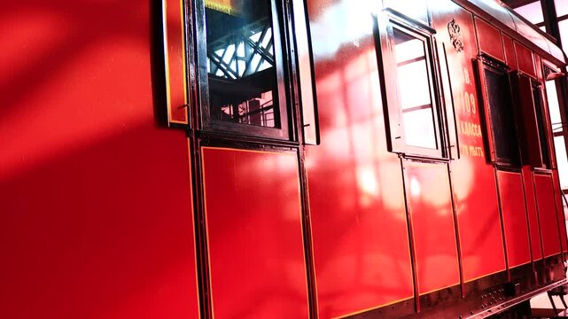 A red train car sits inside a busy train station, ready for its next journey