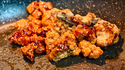 Crispy honey fried chicken pieces sizzle in a hot skillet while being coated in a sweet and savory Asian-style glaze as they cook