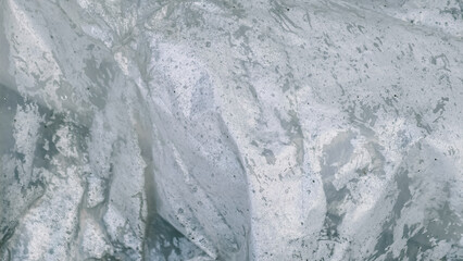 The abstract pattern of wet plastic resembles weathered rock formations and flowing water