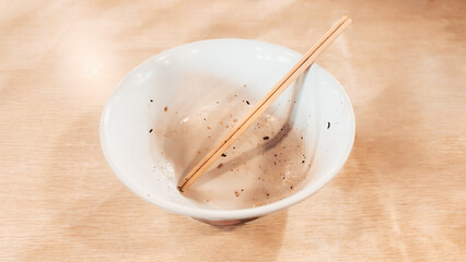 A bowl of leftovers from a meal of wonton noodles, accentuating the emptiness and tranquility of the aftermath