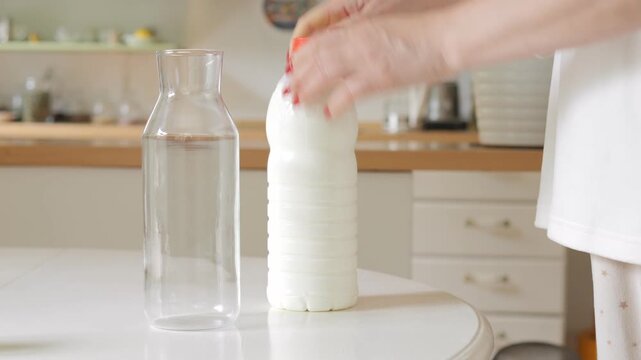 Round white table with a white tablecloth is set up in a kitchen. A white vase is placed on the table, and a potted plant is situated nearby. The kitchen is well-equipped with various items