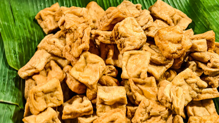 Golden fried tofu cubes piled high on vibrant green banana leaves ready to eat