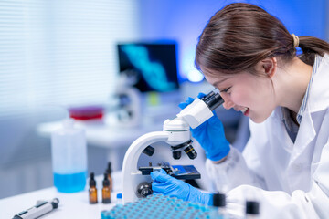 Asian female scientist is using a microscope in a modern laboratory